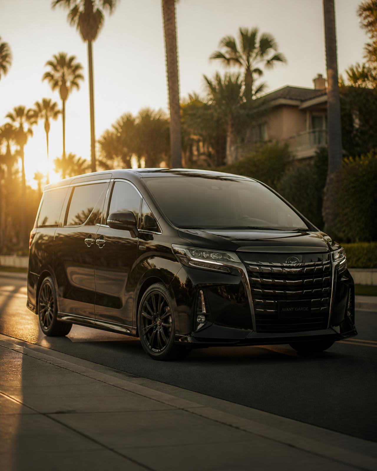 Modern black passenger minivan parked on a Southern California street at golden hour